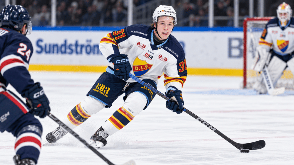 Fred Nord i Djurgårdens matchtröja under en ishockeymatch, där han för pucken framåt på isen med en motståndare framför sig.